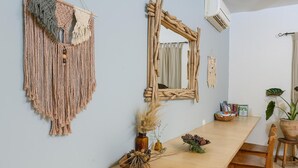 Um quarto com uma longa mesa de madeira, um pendente de macramé e um espelho rústico.