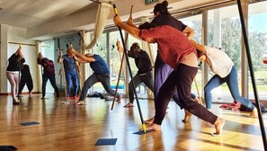 A group of people practicing yoga in a room with large windows and wooden floors. - Jordan Valley Birding Lodge (Emek HaMaayanot)