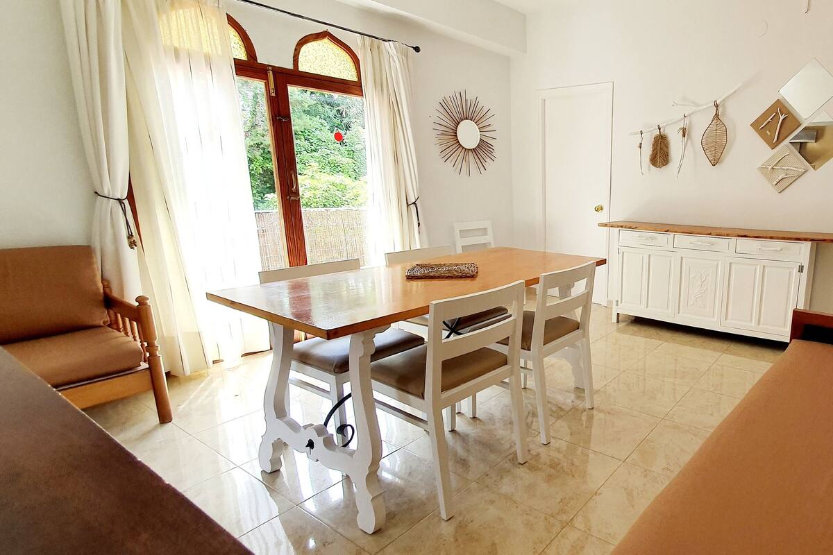 Un coin repas avec une table en bois et des chaises blanches, un meuble blanc et un canapé marron.