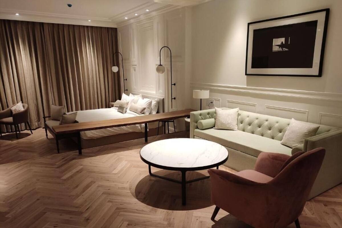 A hotel room with a bed, a sofa, a round coffee table, and a chair.