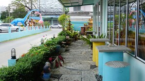 Un chemin bordé de plantes en pot qui mène à un bâtiment doté de grandes fenêtres.