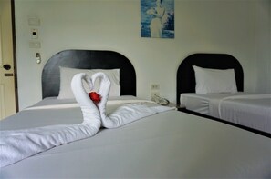 Een hotelkamer met twee bedden, elk met een zwart hoofdbord en witte beddengoed. Daarboven hangt een schilderij aan de muur.
