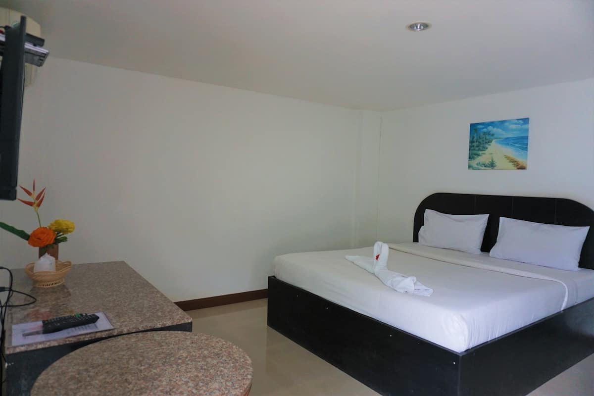 Habitación de hotel con una cama, una mesita pequeña, un control remoto y un cuadro en la pared.