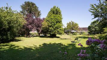 A well-maintained garden with a lawn, various trees, and a gazebo.