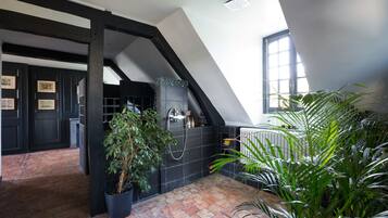 Une pièce avec un plafond en pente, une décoration aux couleurs noir et blanc, un sol carrelé et plusieurs plantes en pot.