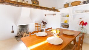 A rustic dining room with a wooden table, chairs, and a fireplace. - Son Sant Andreu (Petra)