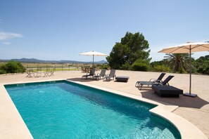 Una piscina al aire libre de temporada, sombrillas, tumbonas