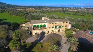 A large, historic building with multiple green archways, a courtyard, and a swimming pool. - Son Sant Andreu (Petra)