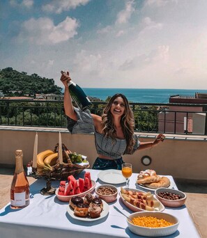 A woman celebrating with champagne on a rooftop terrace with a scenic view of the sea and buildings. - Guest House Medin (Petrovac)
