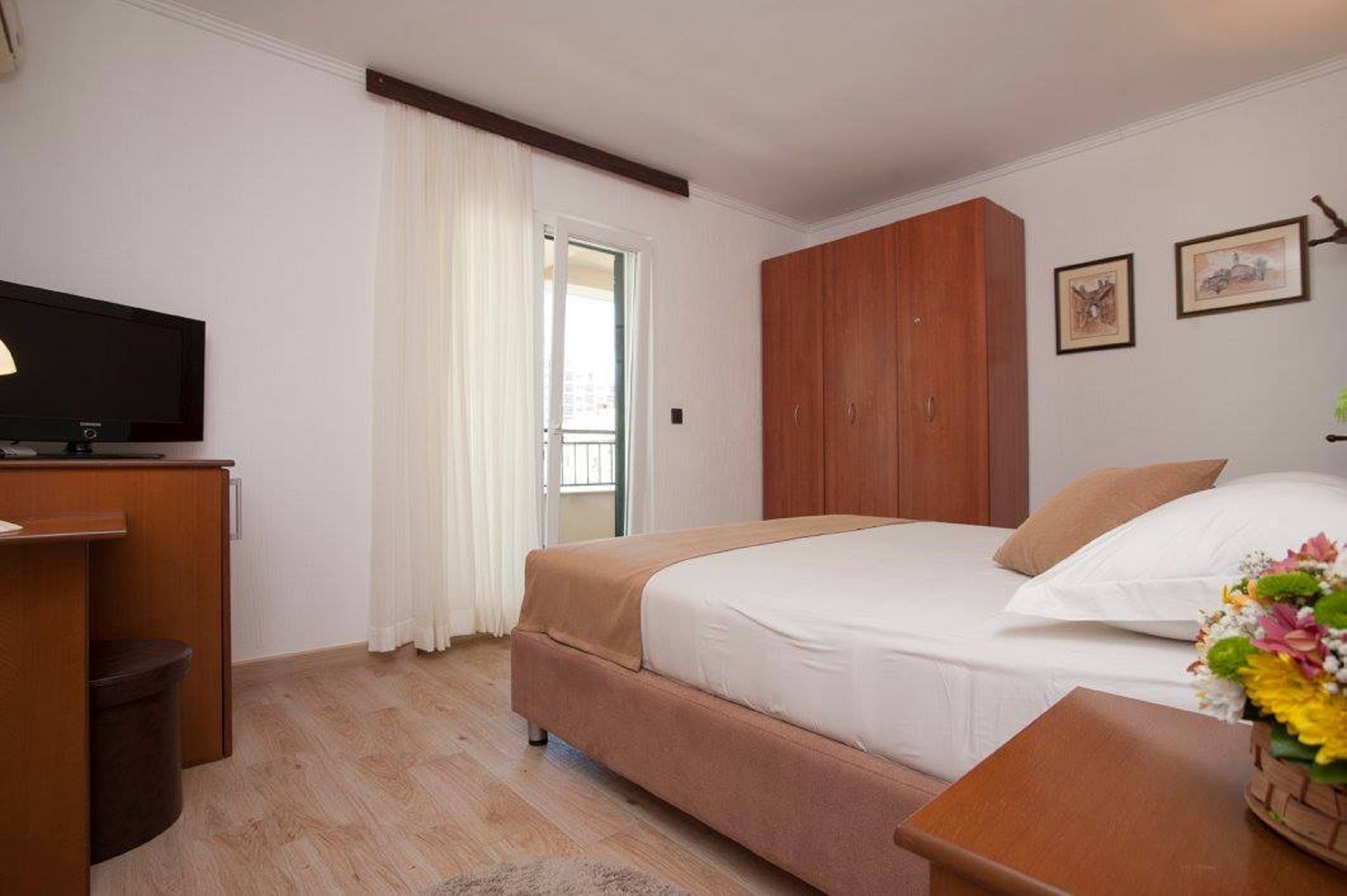 Quarto com cama, televisão, guarda-roupa e escrivaninha.