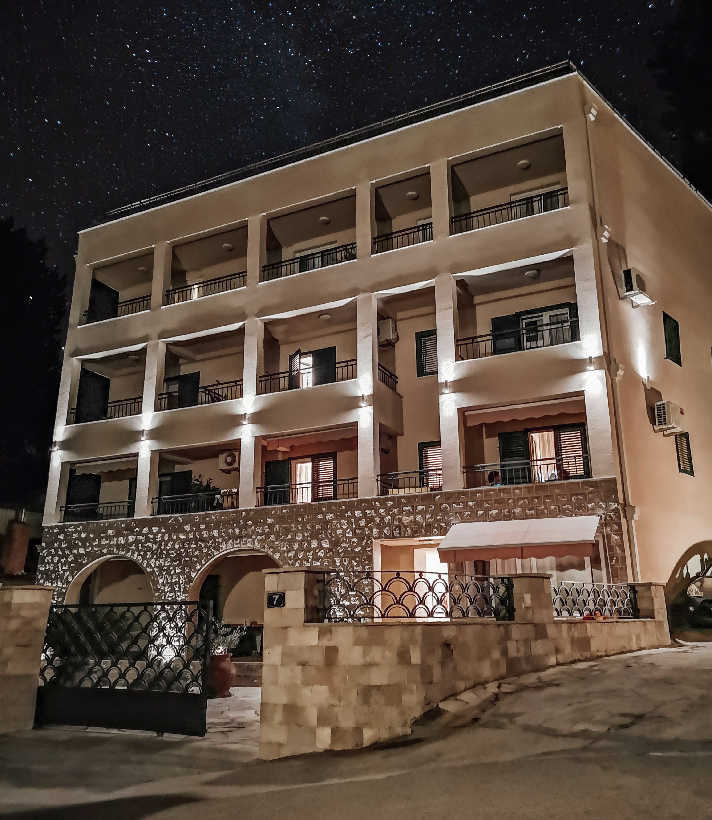 Un hôtel à plusieurs étages doté d’une cour intérieure, de balcons à chaque étage et d’une entrée en forme d’arc en pierre.