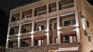 A multi-story hotel with a central courtyard, balconies on each floor, and a stone archway entrance.