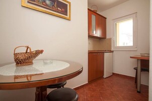 Una cocina compacta con una mesa redonda de vidrio, una cesta de mimbre y armarios de madera.