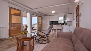 Un'ampia zona giorno con divano, poltrona a dondolo, tavolo da pranzo e cucina sullo sfondo.