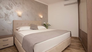 Una camera da letto con un letto grande, due lampade sui comodini, un comodino e un condizionatore d'aria.