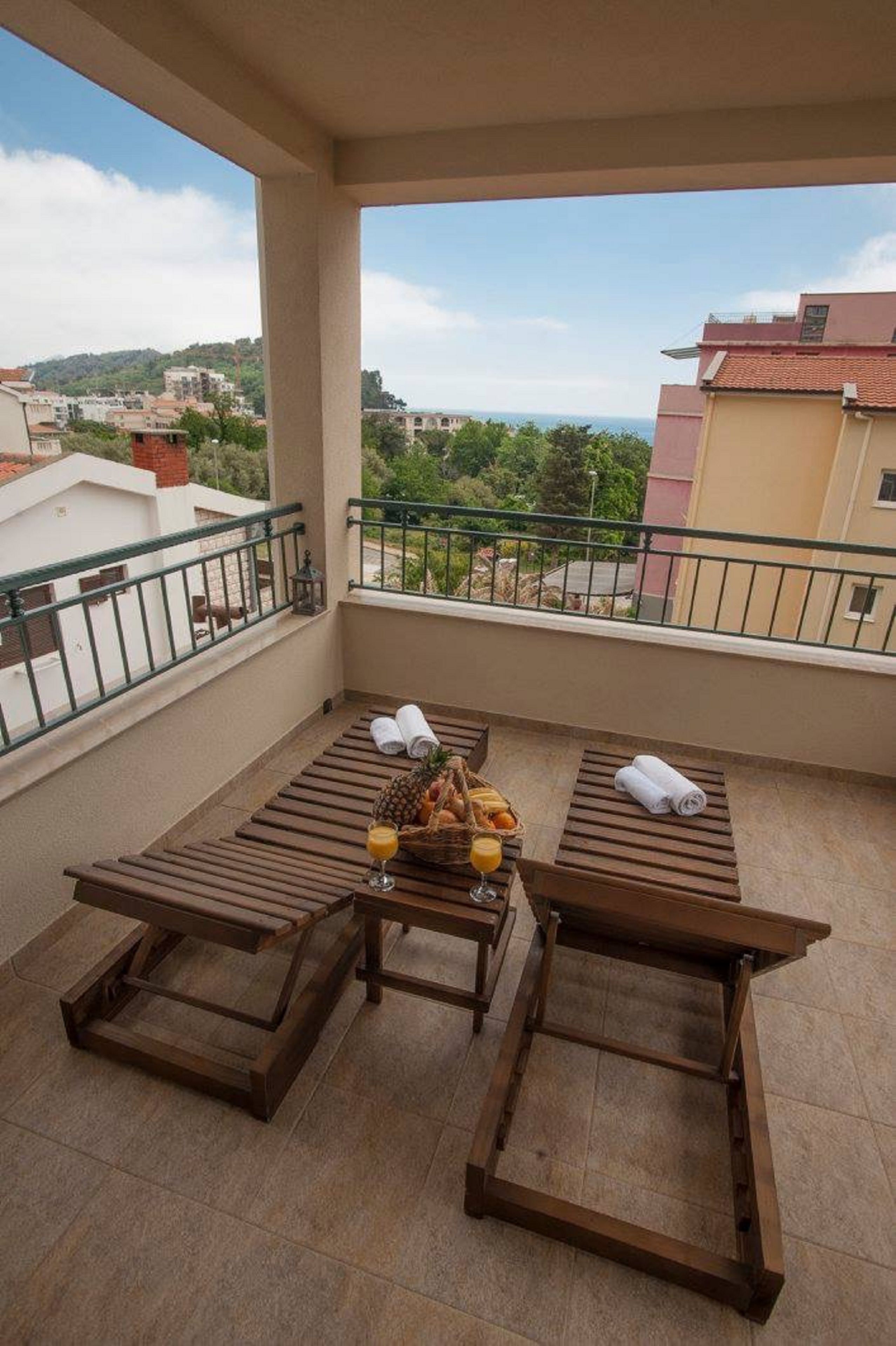 A balcony with wooden loungers, a fruit basket, and a glass of orange juice.