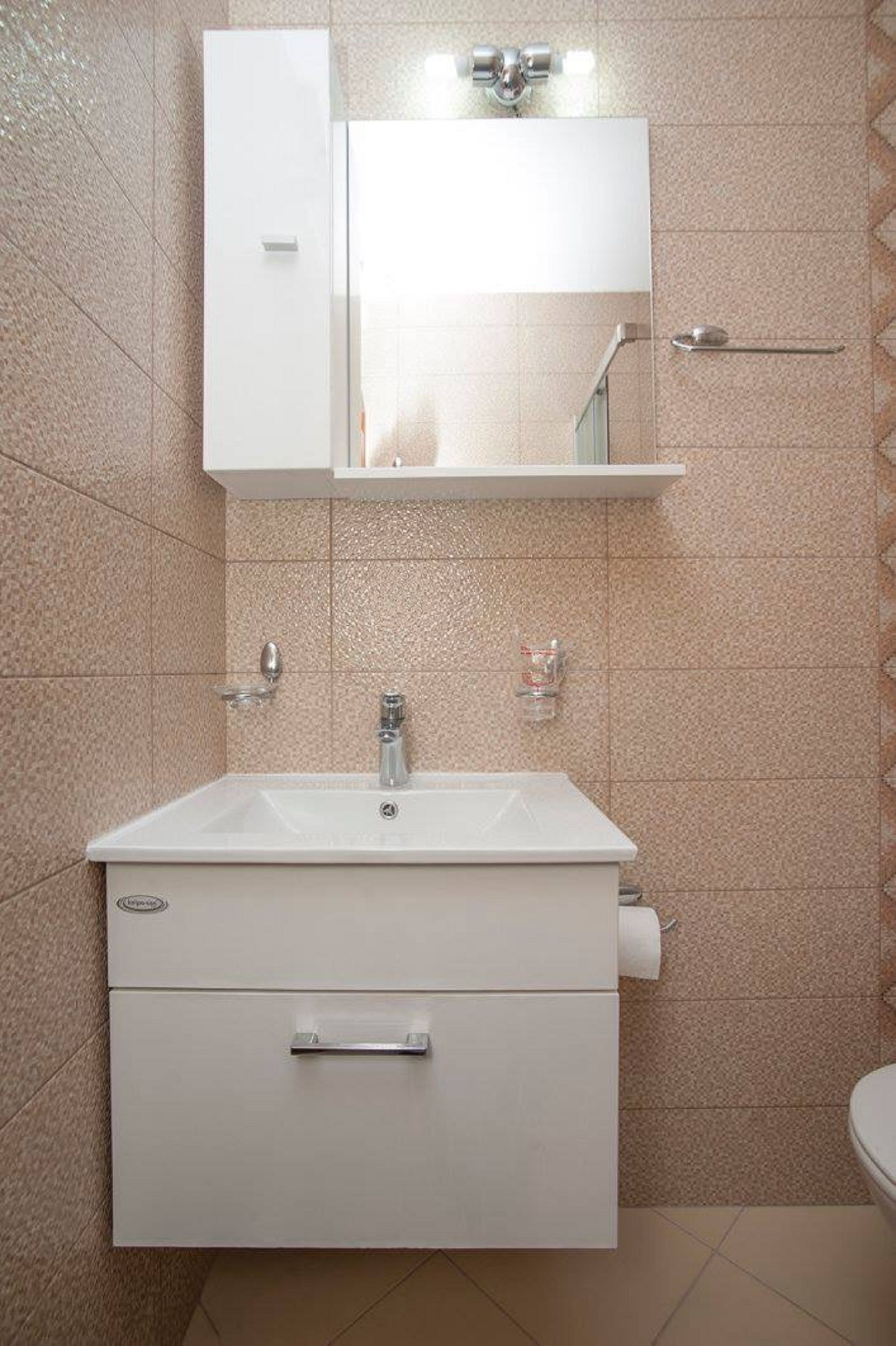A bathroom with a white sink, a mirror above it, and a towel rack.