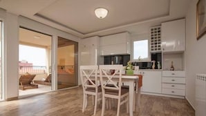 Una cucina moderna con mobili bianchi, un tavolo da pranzo con sedie e vista sul balcone esterno.