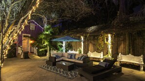An outdoor patio area with a sofa set, a coffee table, and an umbrella. - Best Location 7BR Next to FR Quarter! By YouRent (New Orleans)