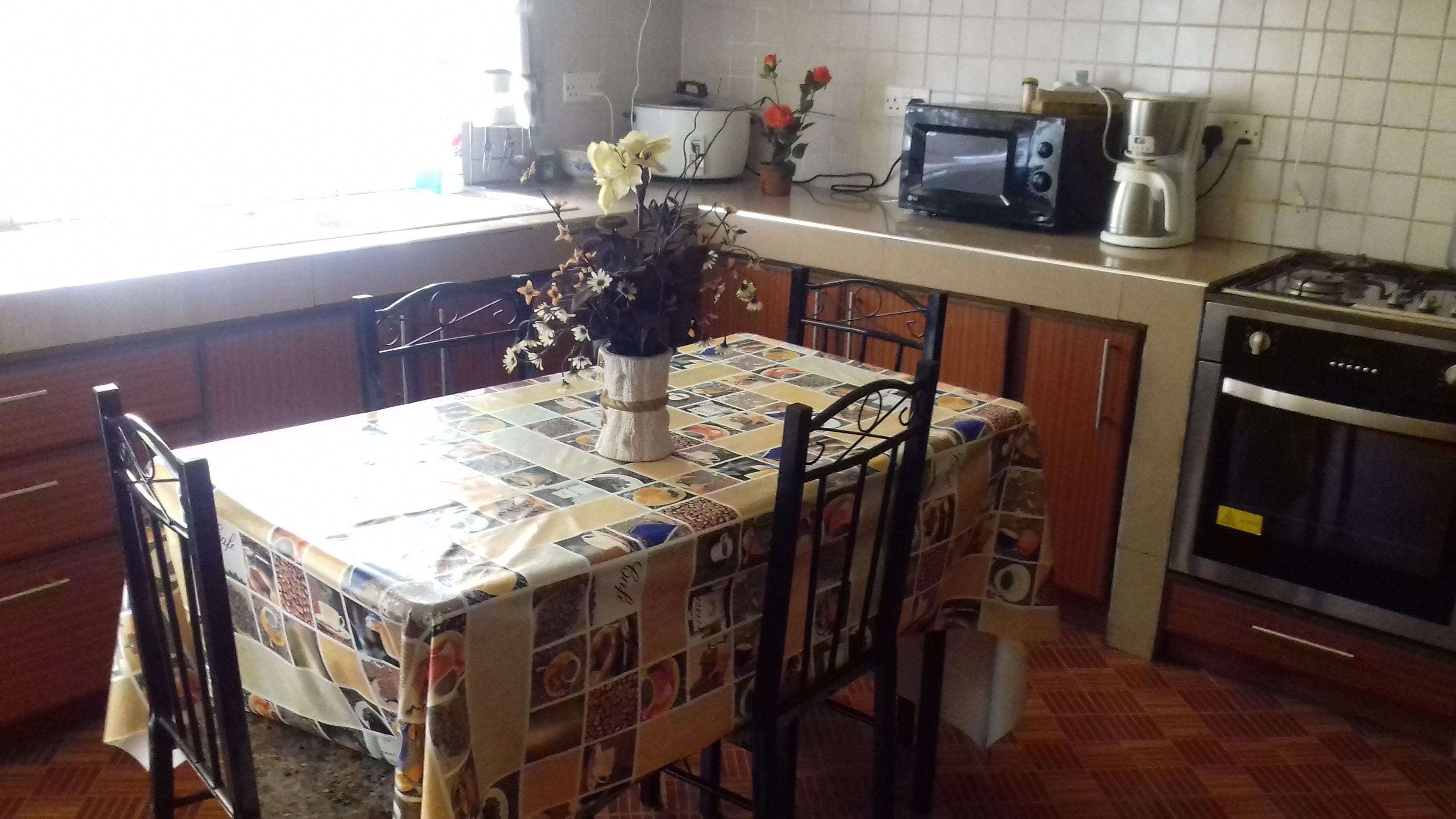 Una cocina con salpicadero de azulejos, microondas, cafetera y estufa.