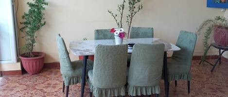 Een eethoek met een tafel en stoelen, een potplant en een wandlamp.