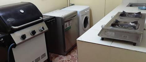 A compact kitchen with a gas stove, a washing machine, and a small refrigerator.