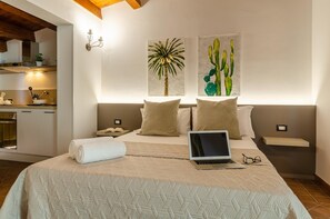 A bedroom with a bed, a laptop, and a painting of cacti on the wall. - Nonna Germina (Roccalumera)