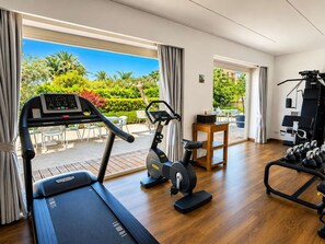 A hotel room with a treadmill, exercise bike, and dumbbells.