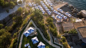 An aerial view of a coastal resort with multiple sun umbrellas, a stone pathway, and a beach area. - Domo20 Hotel & Sky Bar (Vico Equense)