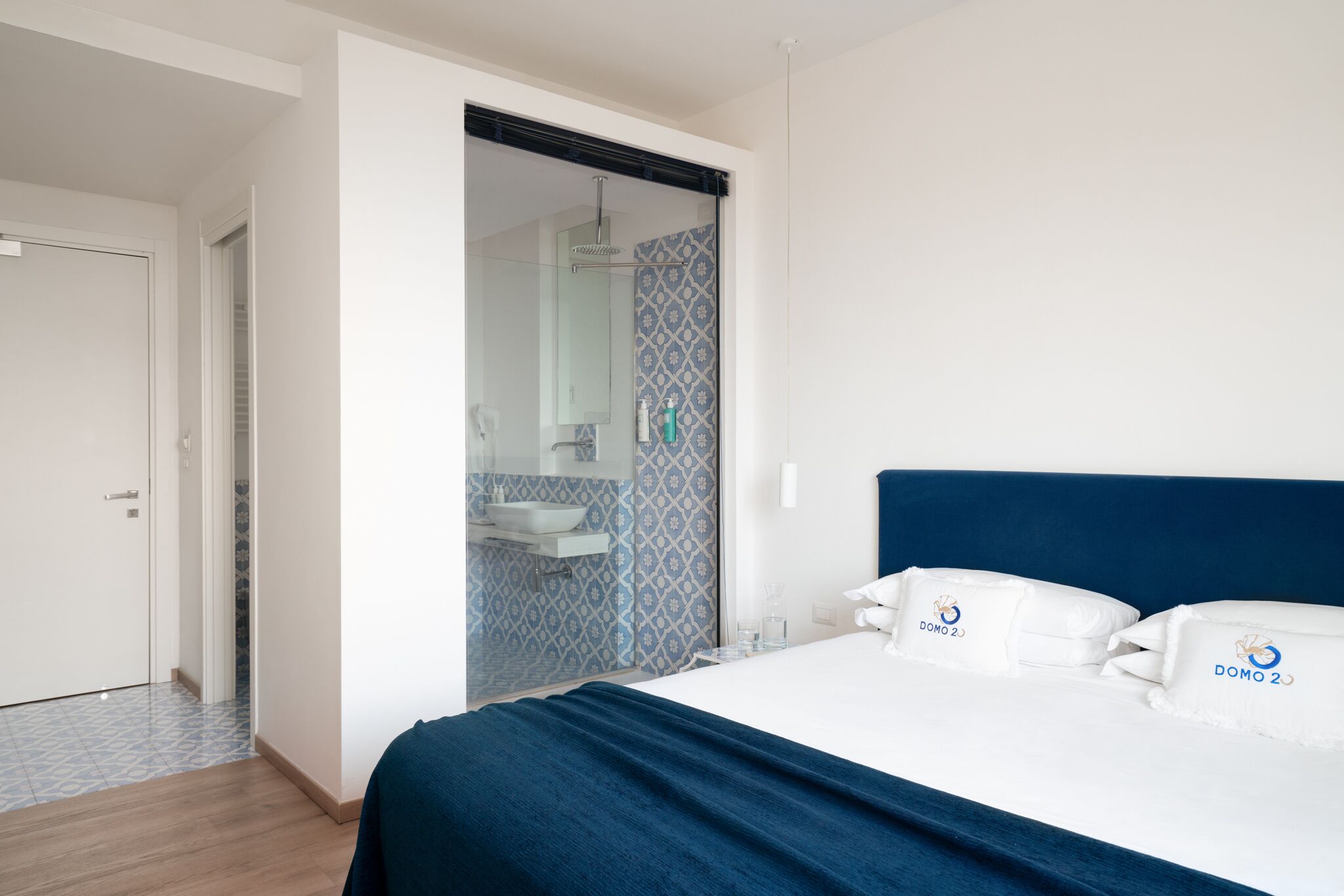A bedroom with a bed, a bathroom with a shower, and a white door.