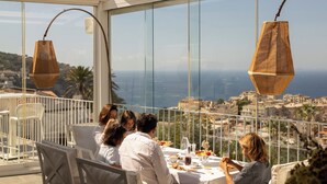 Una terraza con una mesa dispuesta para comer, con vistas a una ciudad costera.