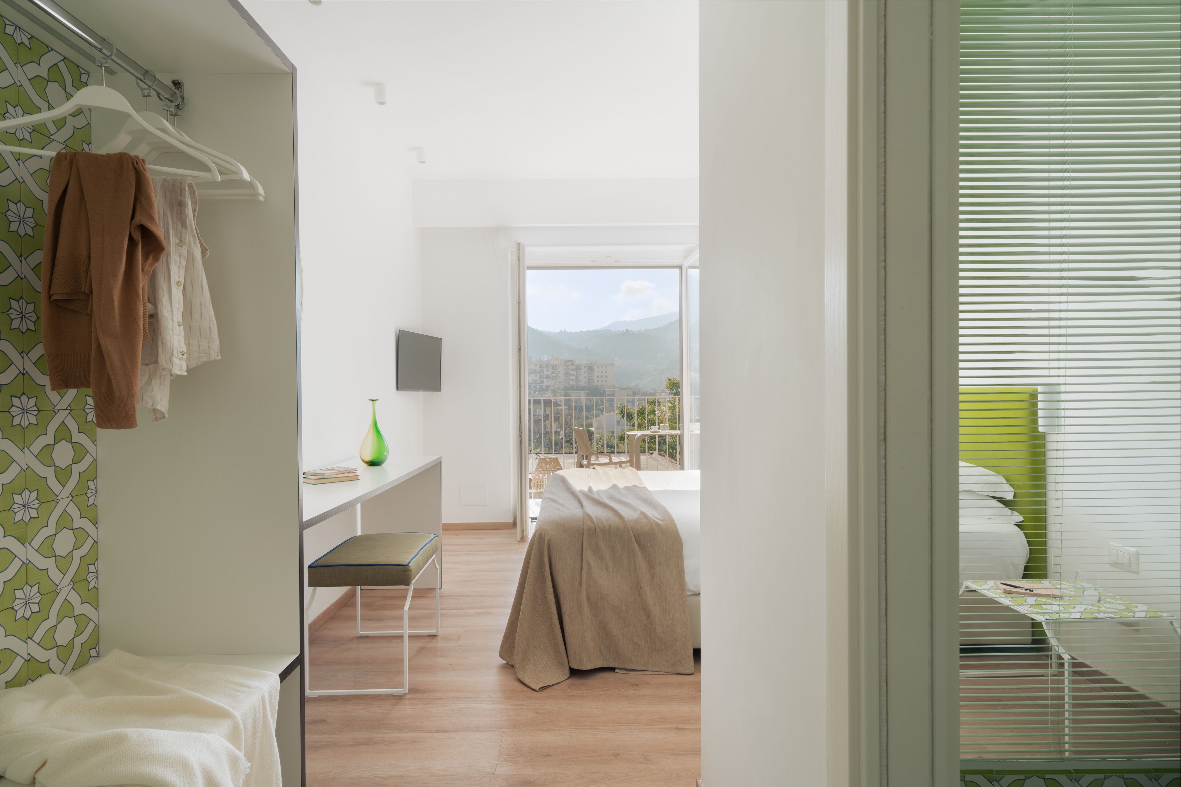 A modern bedroom with a bed, a desk, and a view of the city.