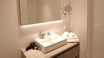 A modern bathroom with a large mirror, a sink, and a shower.