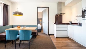 Une chambre d’hôtel moderne dotée d’un coin repas, d’une kitchenette et donnant sur le couloir.