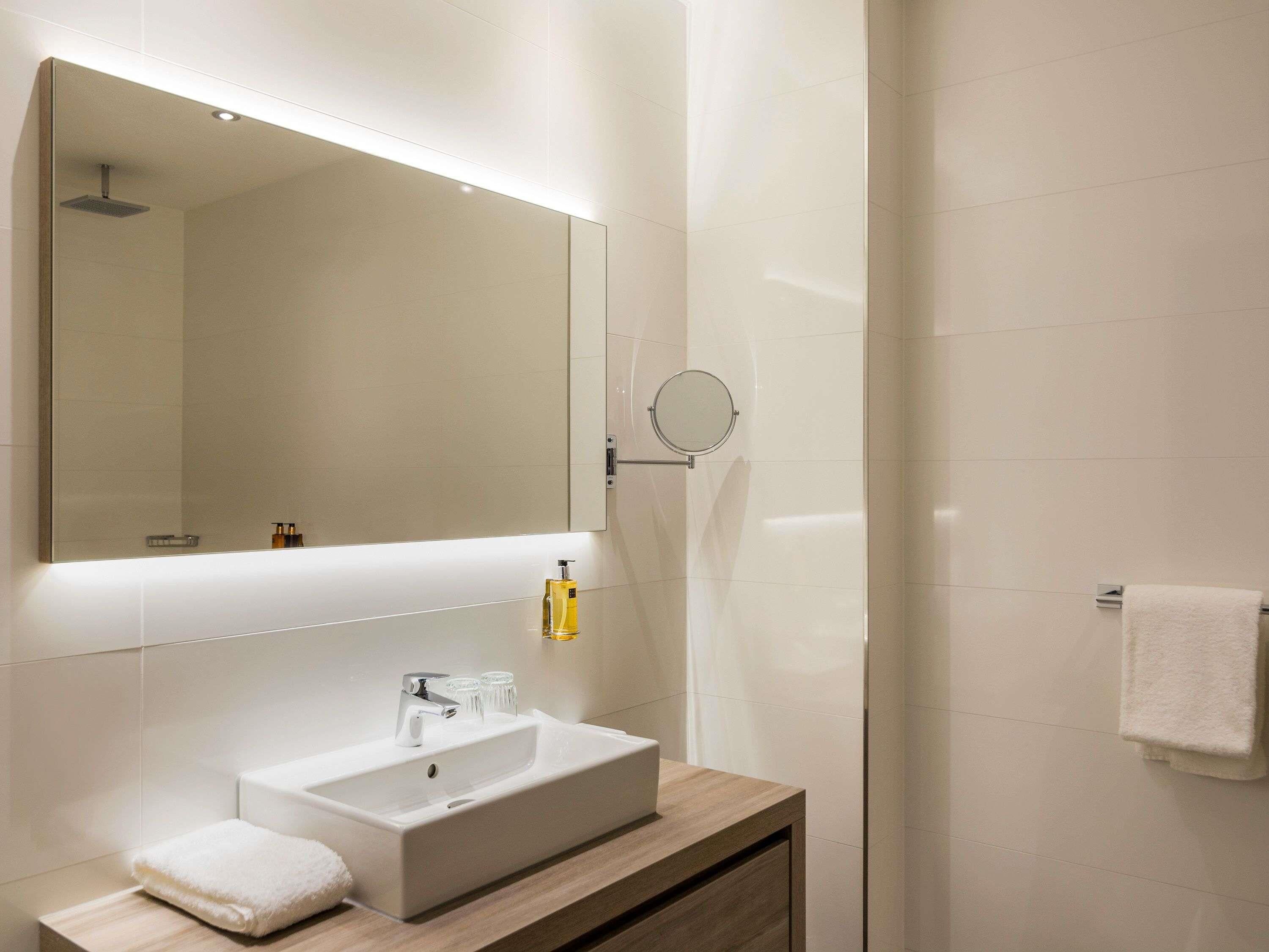 Une salle de bain moderne avec un grand miroir, un lavabo et un porte-serviettes.