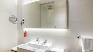 Une salle de bain moderne avec un grand miroir, un lavabo et un porte-serviettes.