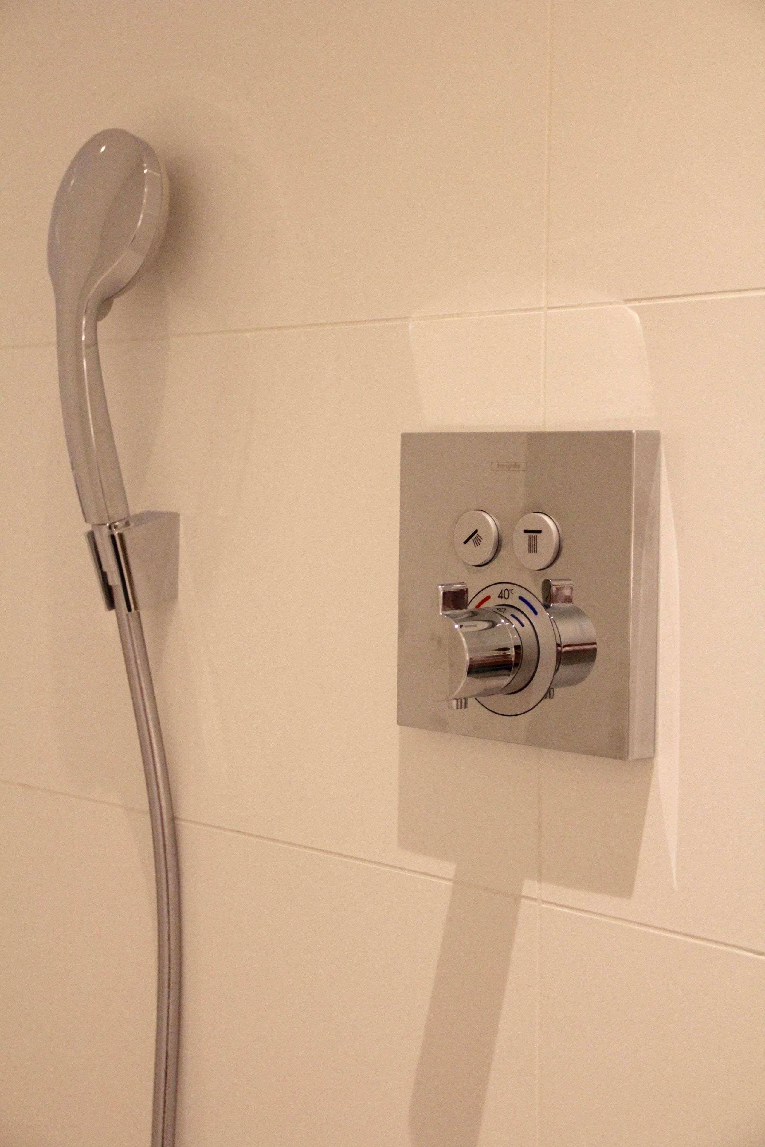 A modern shower control panel with a handheld showerhead.