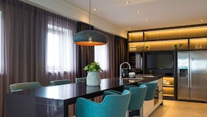 Een moderne keuken met een centraal eiland, barkrukken, een hanglamp en een ingebouwde televisie.