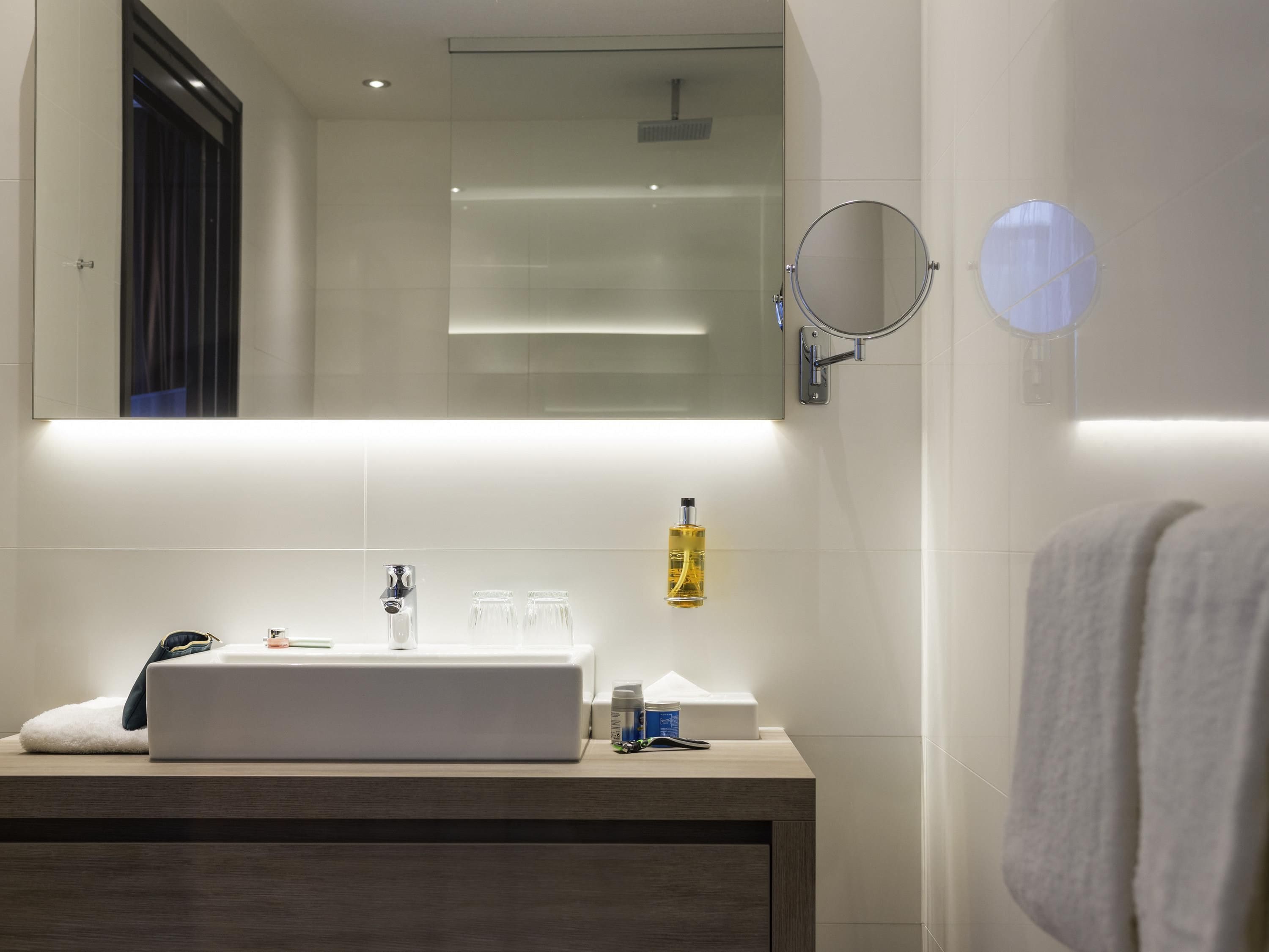 Un baño moderno con un espejo grande, un lavamanos y una toalla colgada en la pared.