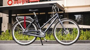 Un vélo d’appartement est garé devant un immeuble sur lequel on peut lire l’inscription « Adagio APARTHOTEL ».