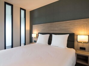 A hotel room with a large bed, two bedside tables with lamps, a dark headboard, and a large window. - Adagio Amsterdam City South (Amstelveen)