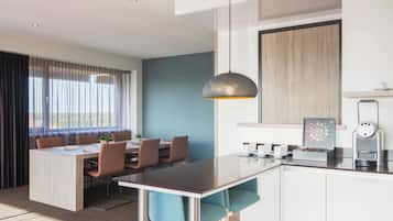 A modern kitchen with a dining area, a coffee machine, and a view of the outdoors.