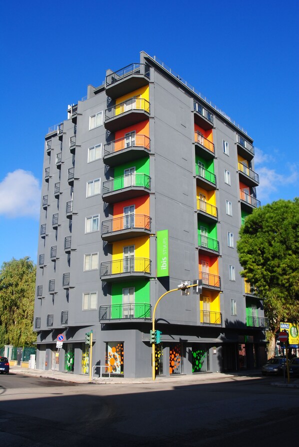 Un edificio de varios pisos con balcones, un letrero verde y una señal de no estacionamiento.