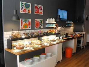 Een buffet met diverse gerechten, een televisiescherm en kunst aan de muur.