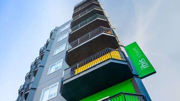 Un immeuble à plusieurs étages, doté de balcons et d’une enseigne verte.