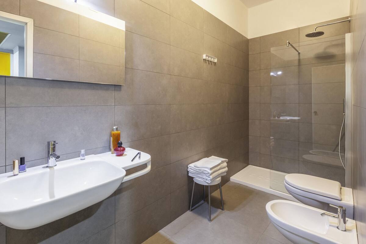 Een moderne badkamer met twee wastafels, een douche en een toilet.