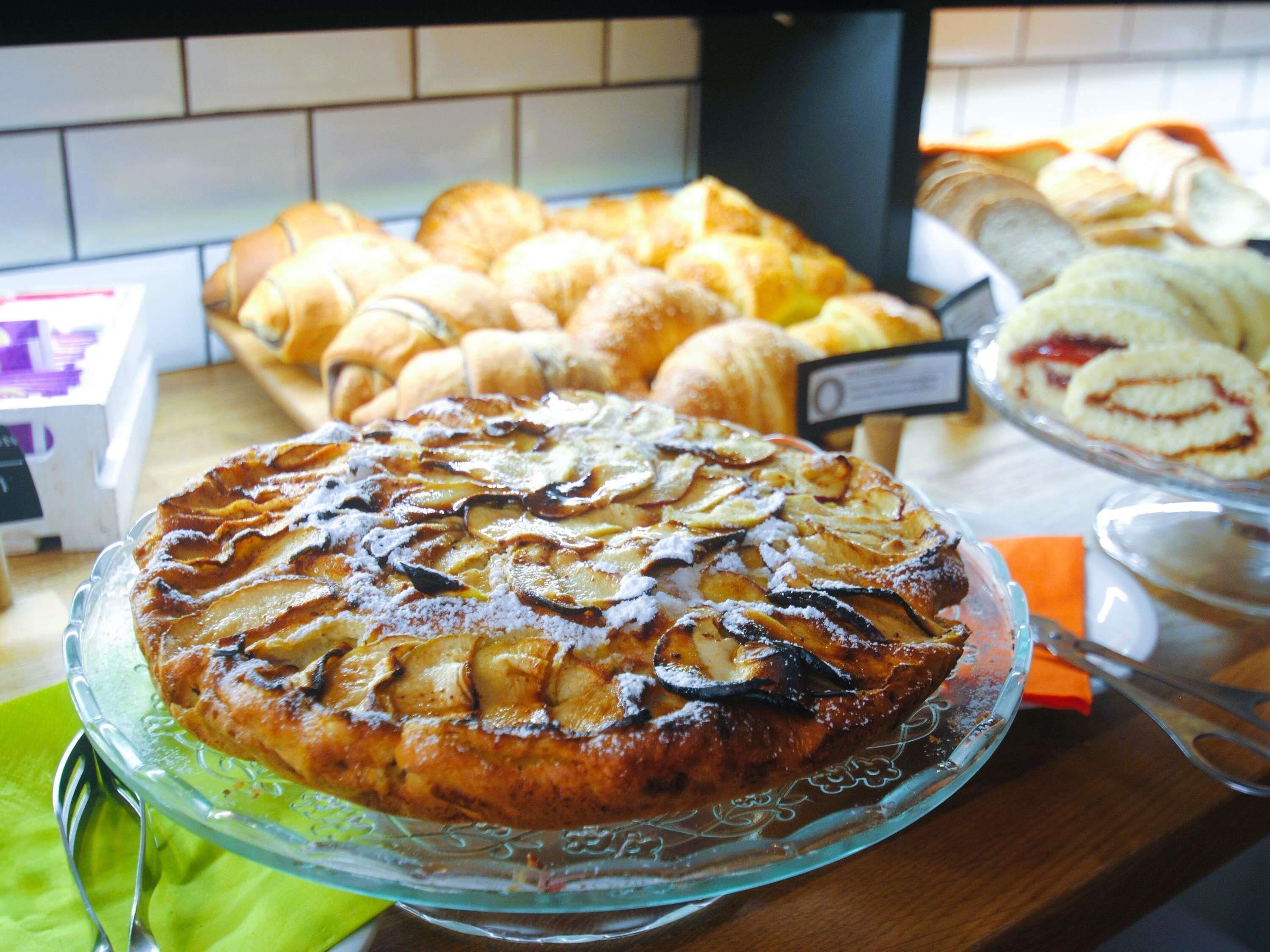 A dessert display with a caramelized apple tart, assorted pastries, and a sign indicating a price.