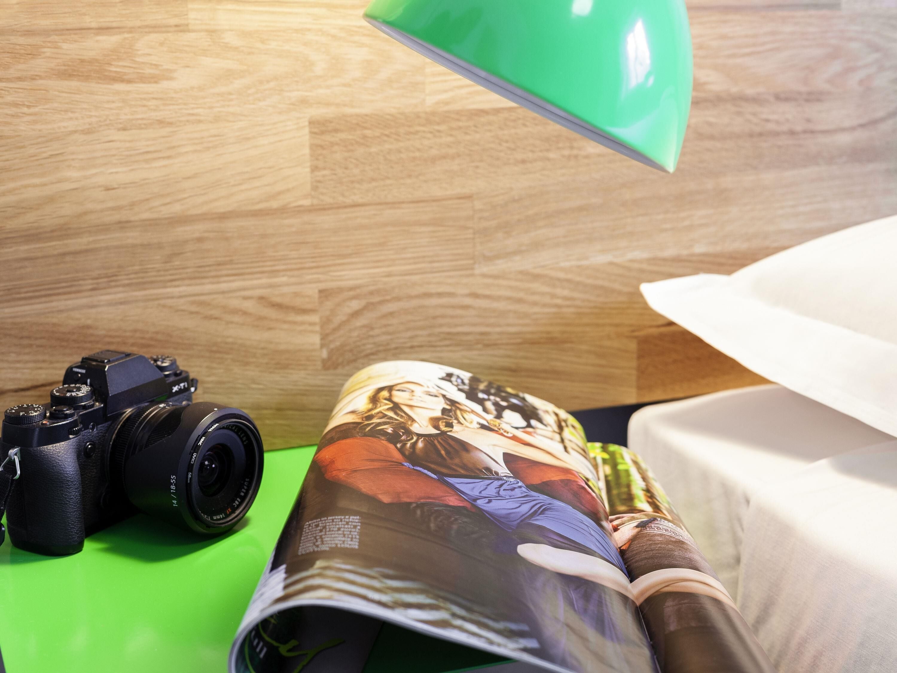 A camera on a green surface, a magazine with a person on the cover, and a white object partially visible.