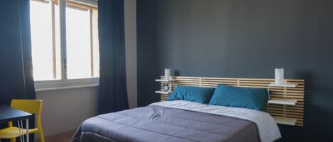 A bedroom with a bed, a desk, and a chair.