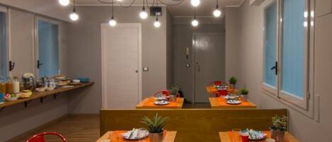 A dining area with wooden tables, red chairs, and hanging pendant lights.